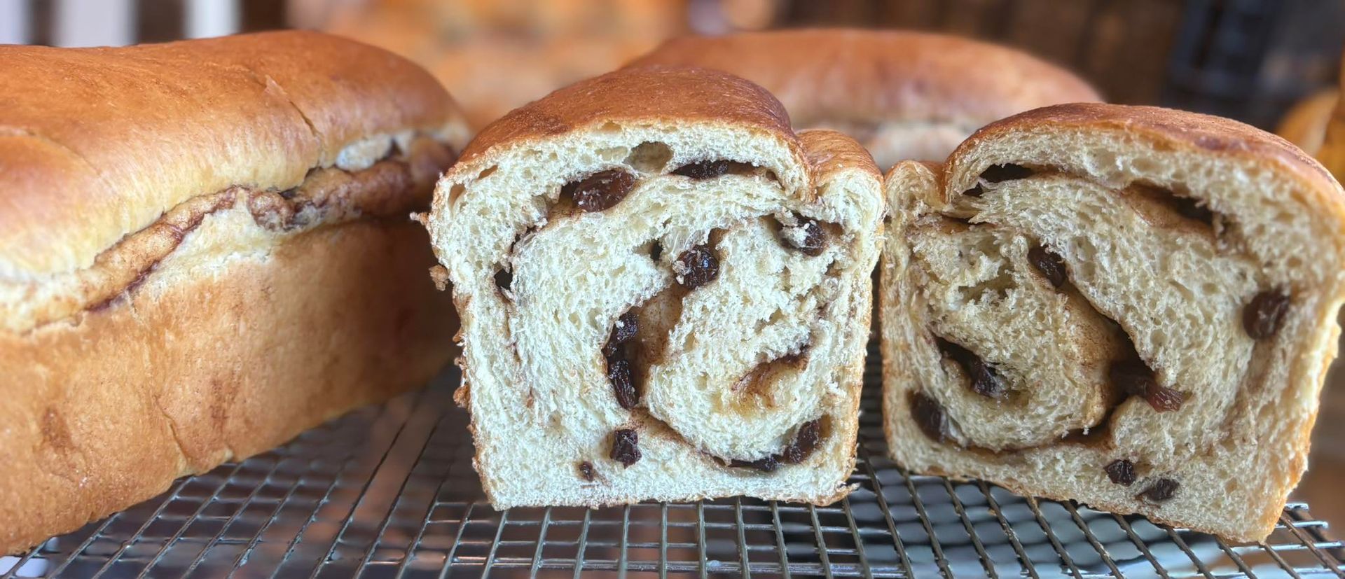 Sliced raisin bread loaf on a cooling rack.