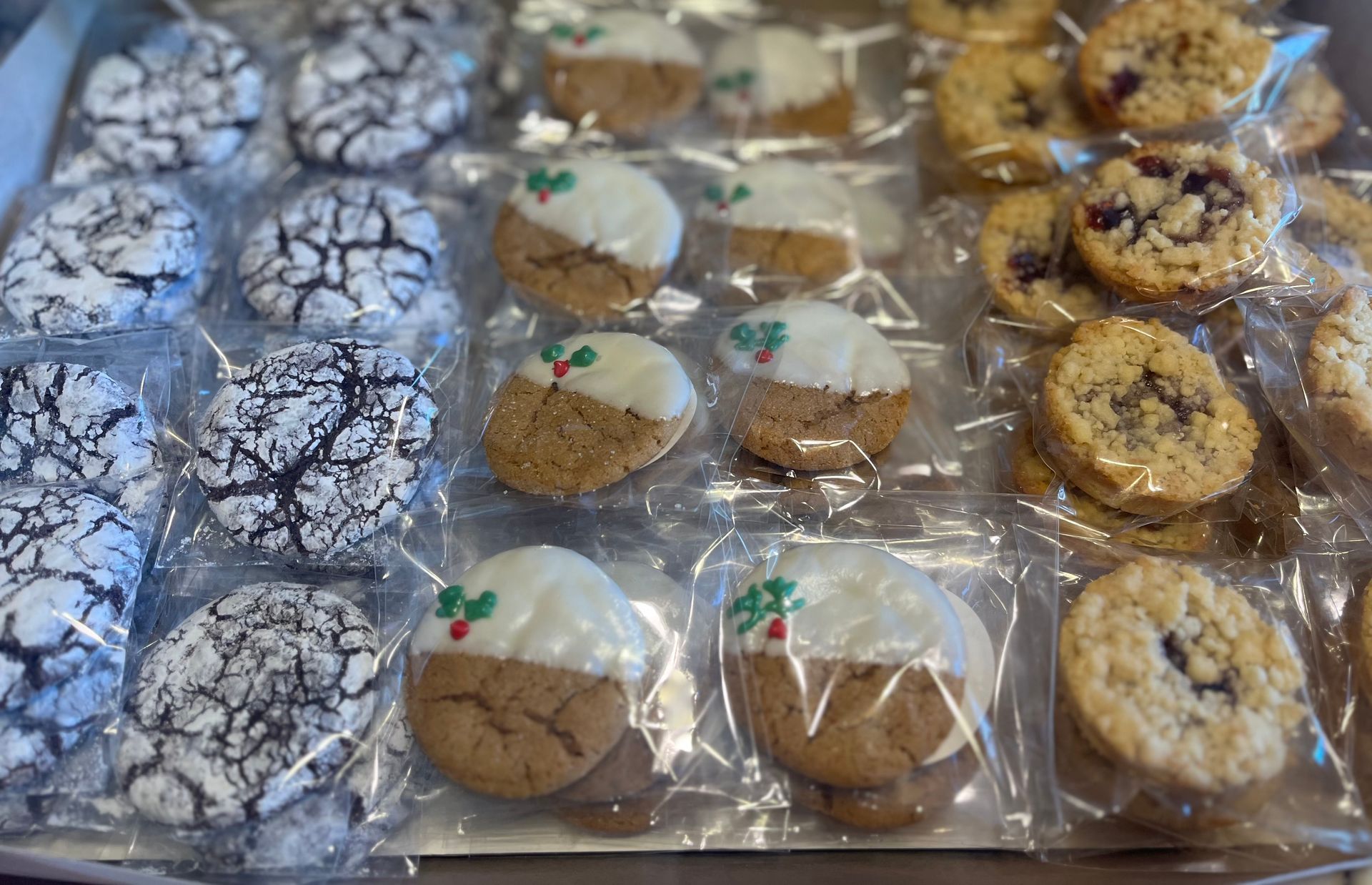 Cookies in cellophane packaging: chocolate crinkles, white-dipped with holly, and crumble-topped.