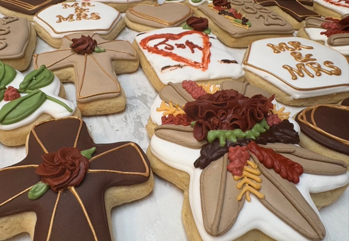 Decorated sugar cookies with wedding-themed frosting. Cross, heart, and square shapes, with fall colors.