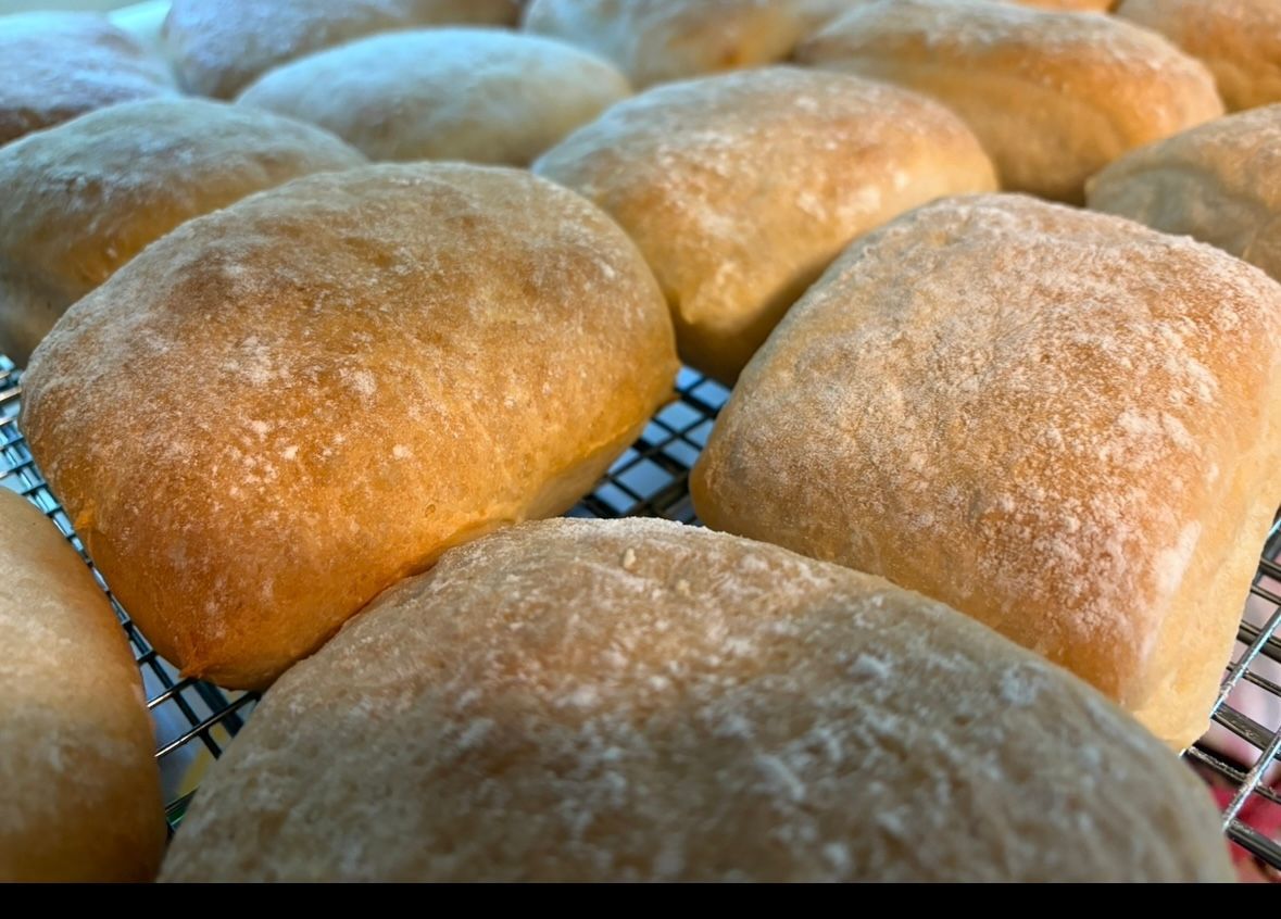Golden-brown rolls dusted with flour on a wire rack.