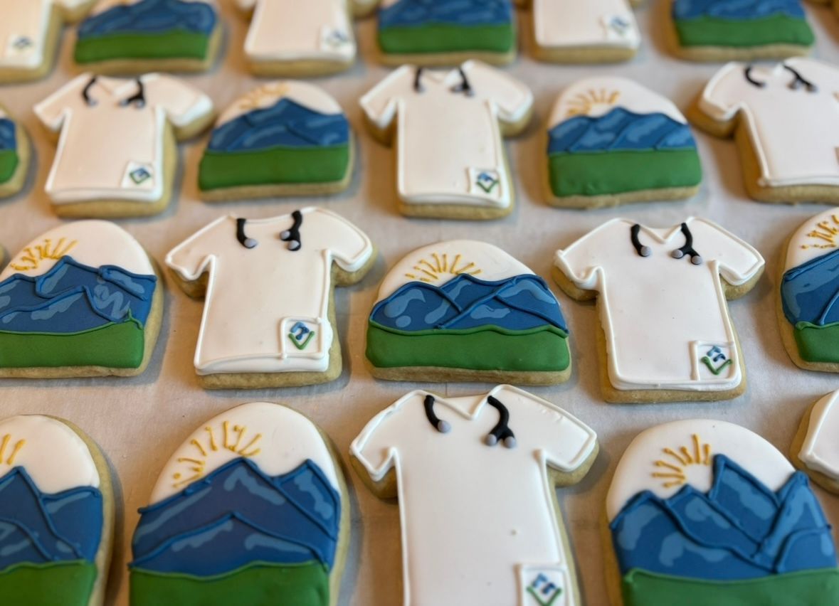 Cookies decorated as mountains and scrub tops. White icing, blue, green, and gold details.
