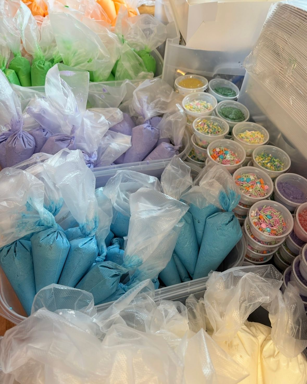Rows of colorful icing bags and sprinkle containers, likely for decorating baked goods.