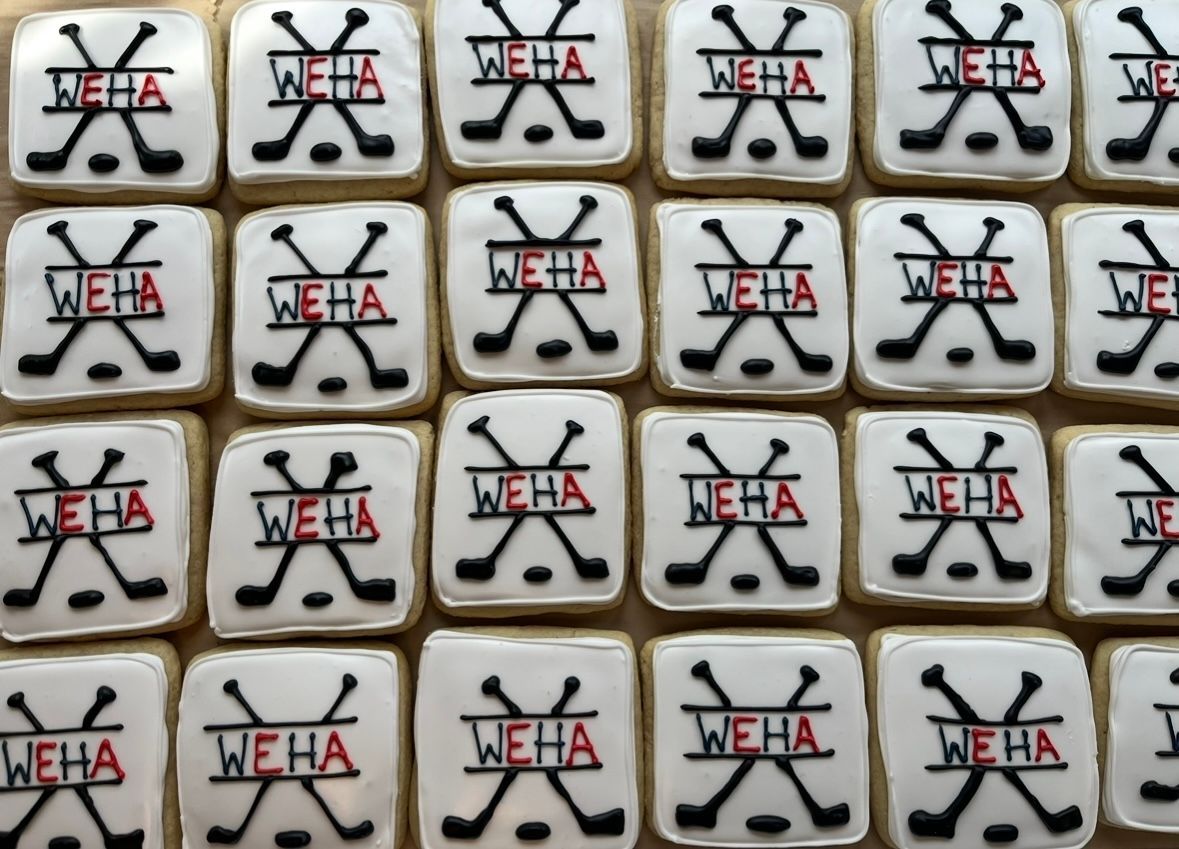 Square cookies with white icing, black hockey sticks and red 