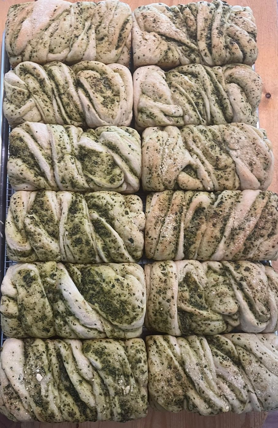 Rows of twisted bread, light and dark green marbled, on a wire rack.