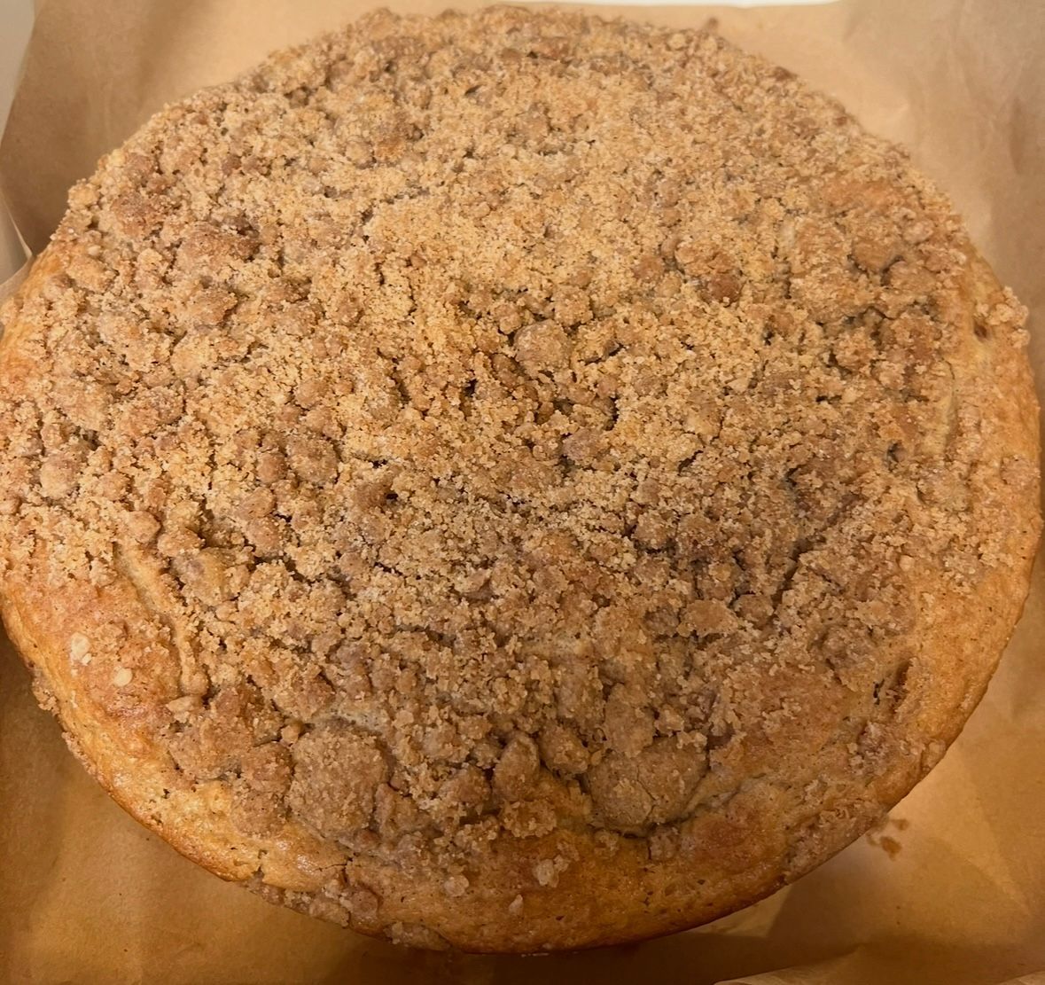 Round coffee cake with a crumb topping on parchment paper.