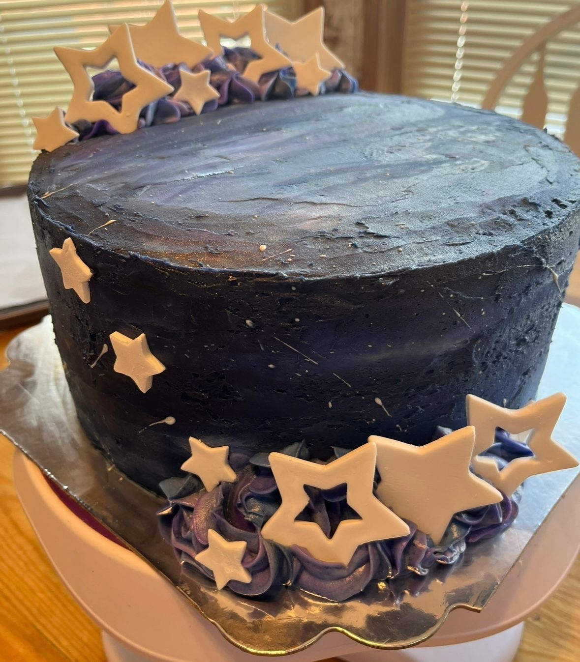 Cake decorated with navy blue frosting, white stars, and purple rosettes.