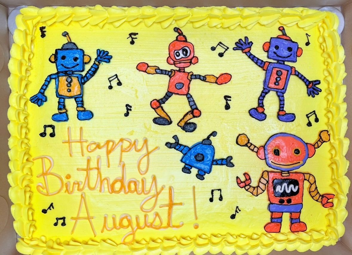 Yellow cake decorated with colorful robot characters and the words 