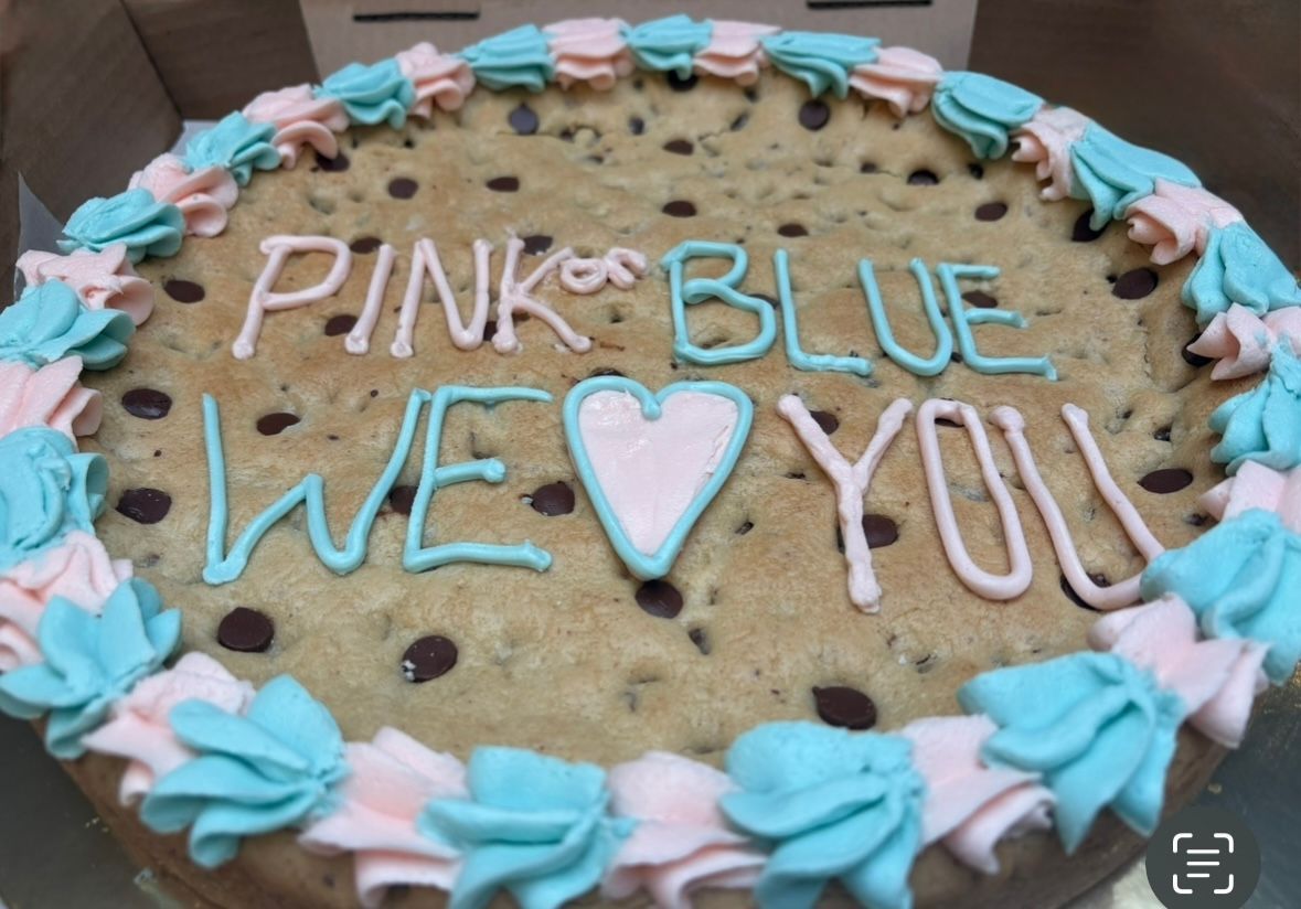 Pink and blue decorated chocolate chip cookie cake for a baby shower.