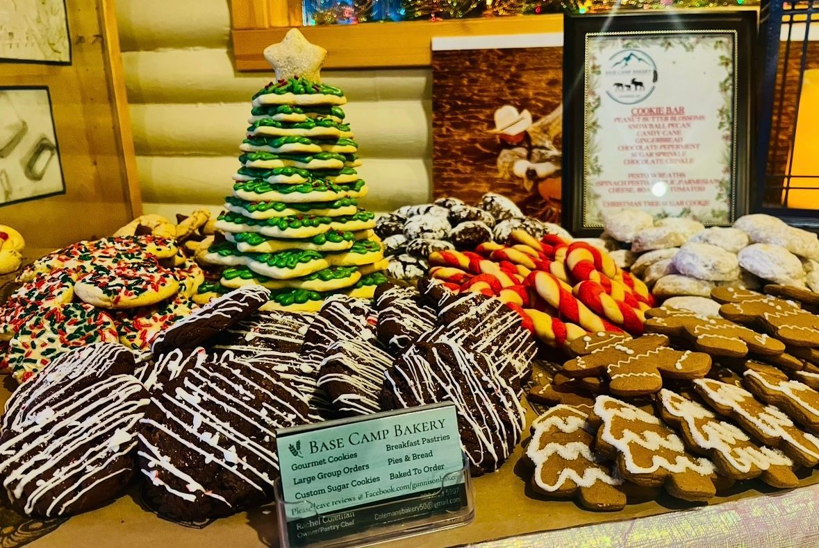 Display of Christmas cookies, including decorated sugar cookies, gingerbread men, and a tree-shaped cake.