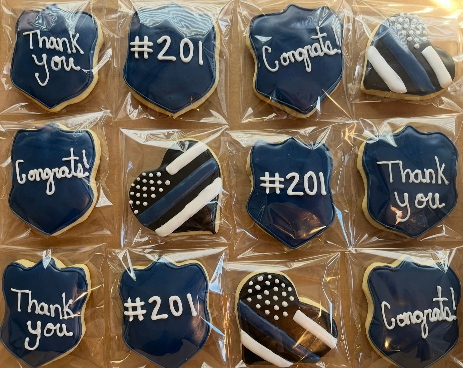 Cookies decorated with blue and white frosting in police badge and heart shapes. Some say 