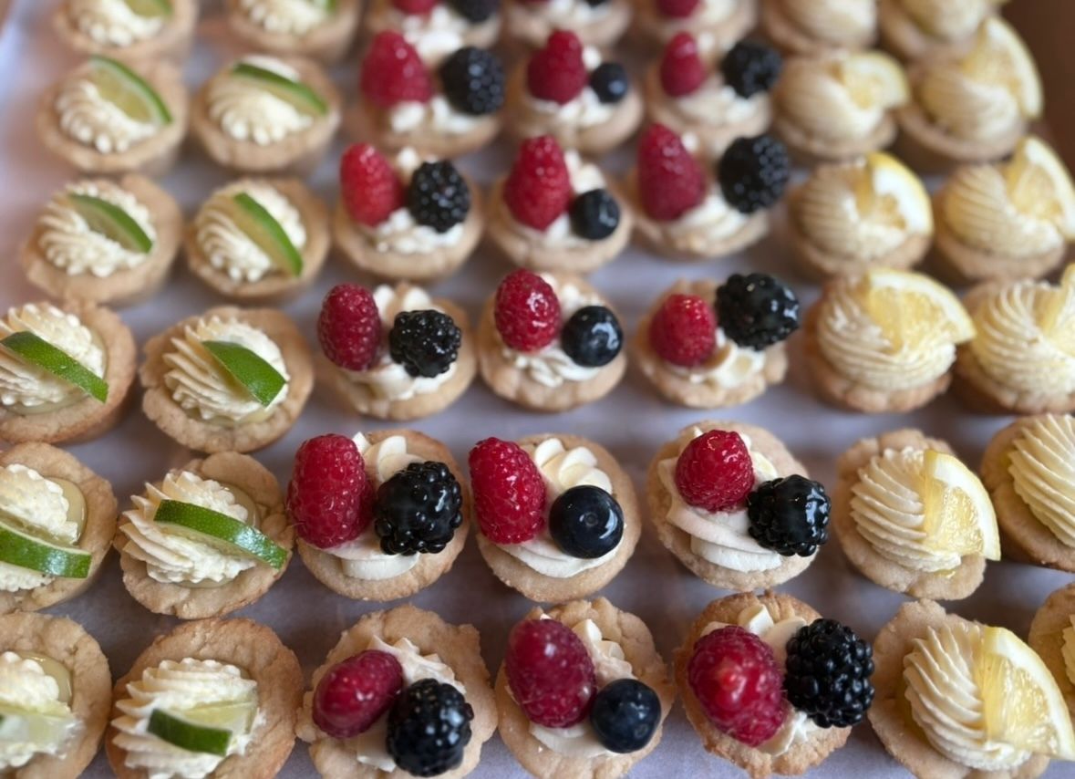 Mini pastries topped with fruit, cream, and lime in a tray. Base Camp Bakery Gunnison, Colorado https://share.google/AgqUzUKNzsb0ThlP5, https://www.facebook.com/BaseCampBakery1, https://www.instagram.com/basecampbakery_81230