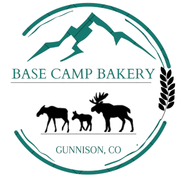 Logo for Base Camp Bakery in Gunnison, CO: mountains, moose family, wheat, teal and black.
