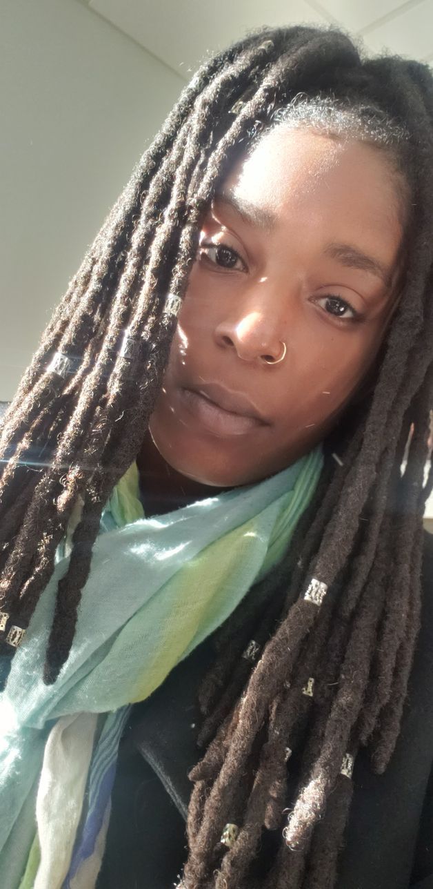 A woman with dreadlocks is wearing a scarf around her neck.