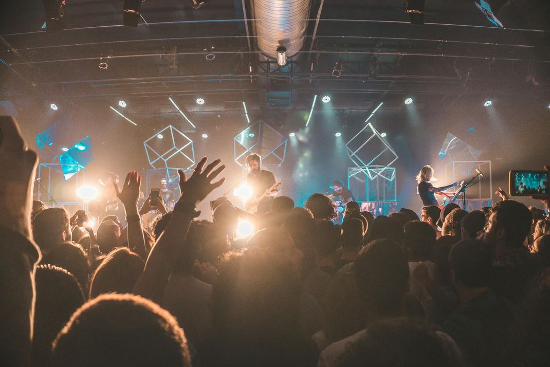 A crowd of people are standing in front of a stage at a concert.