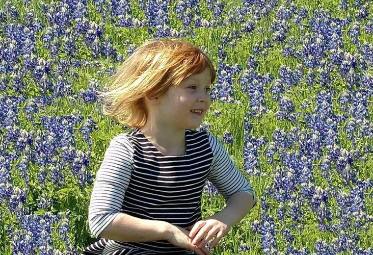 Little Girl Running Through a Field of Flowers