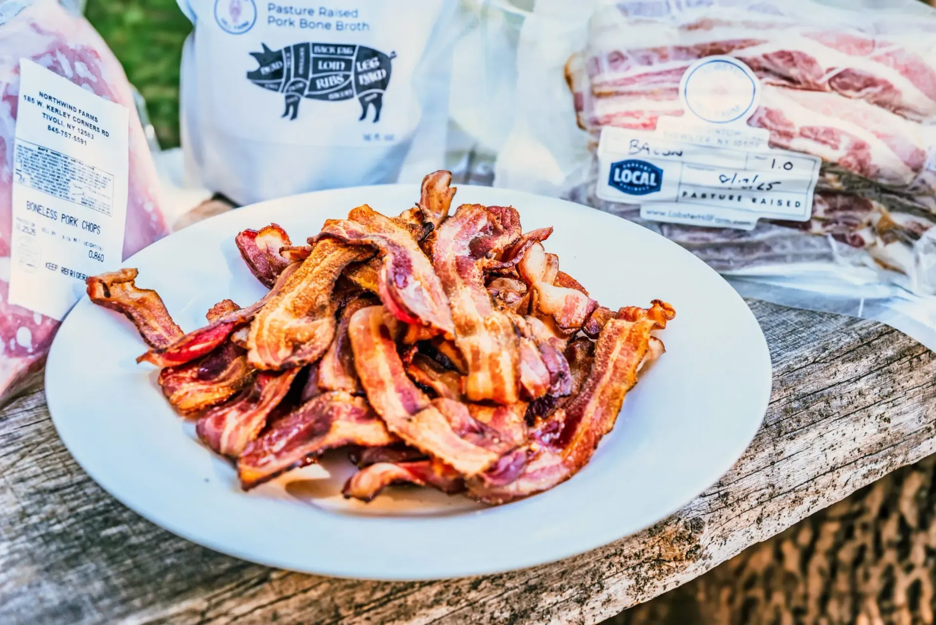 Plate of cooked bacon on a wooden surface with packaged raw bacon and a flour bag in the background.