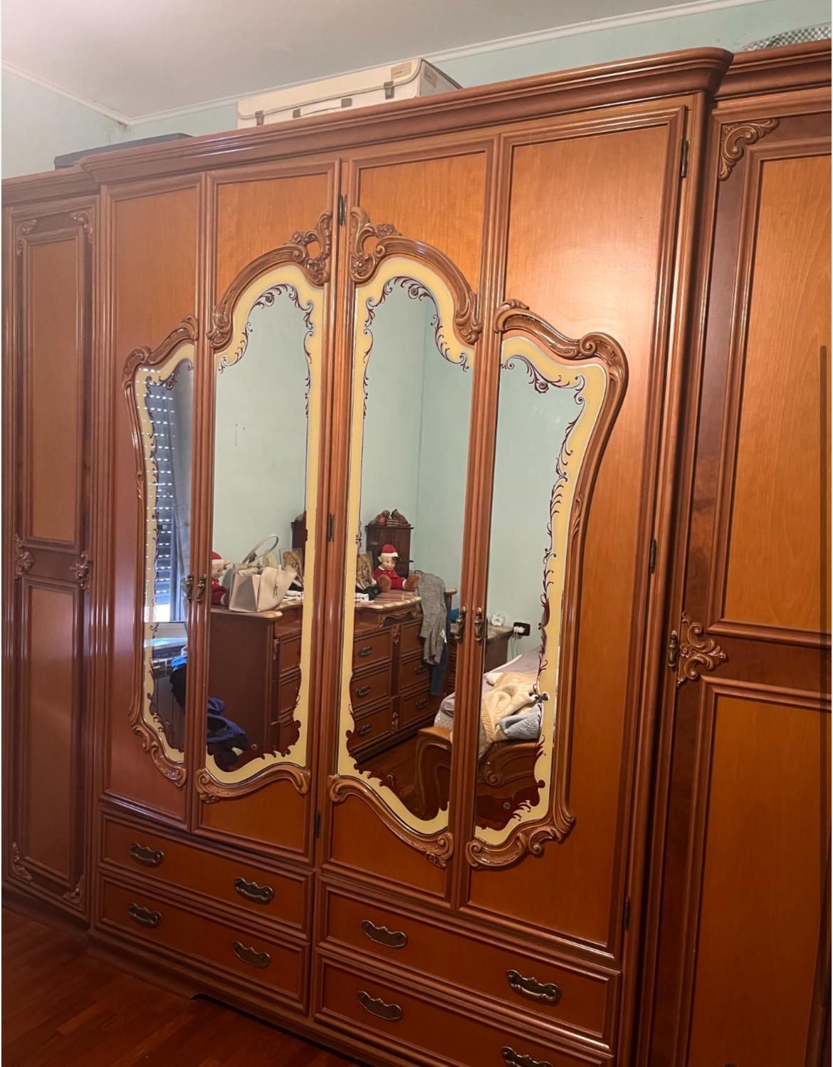 Armadio in legno con ante e cassetti a specchio. Finiture marroni e chiare; riflessi interni visibili.