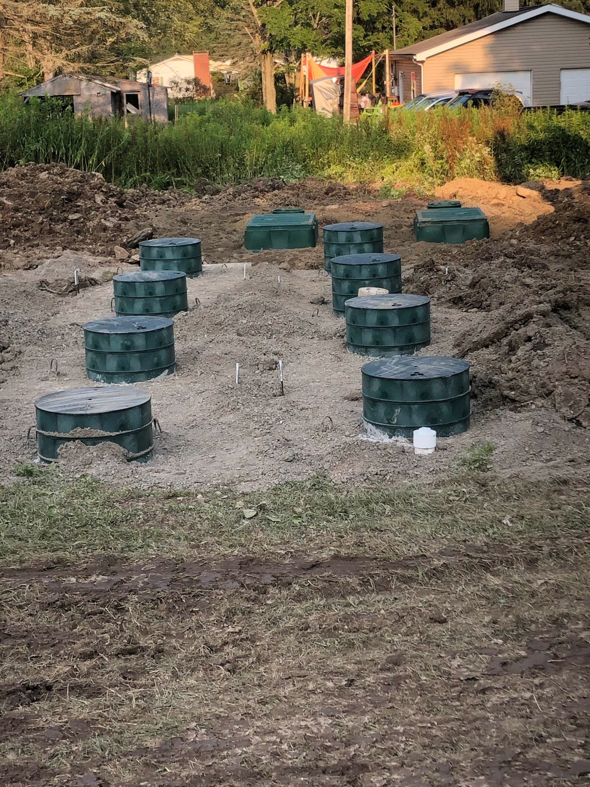 A Row of Septic Tanks Are Sitting in the Dirt in a Field