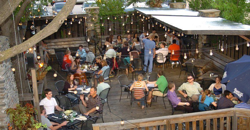 A group of people are sitting at tables outside of a restaurant