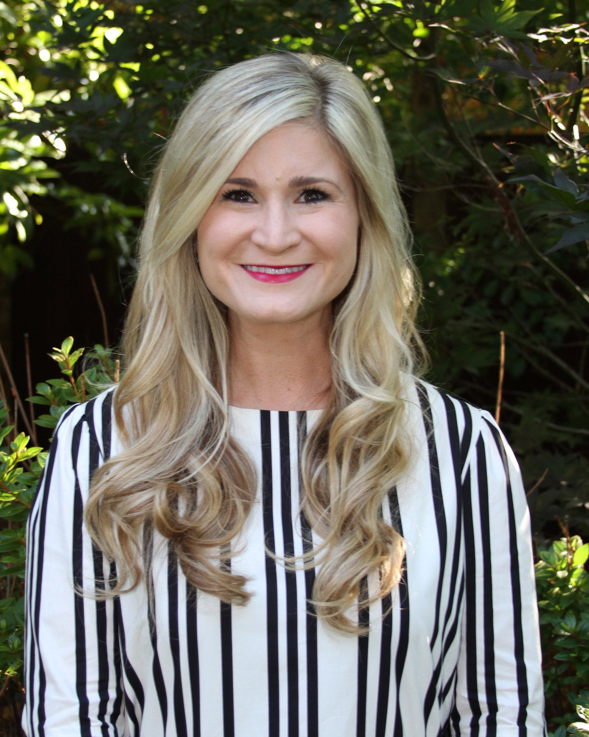 The woman is wearing a striped shirt and smiling for the camera.