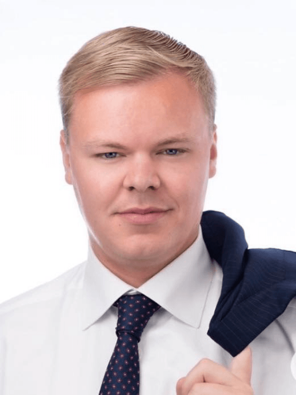 A man in a white shirt and tie is holding a jacket over his shoulder