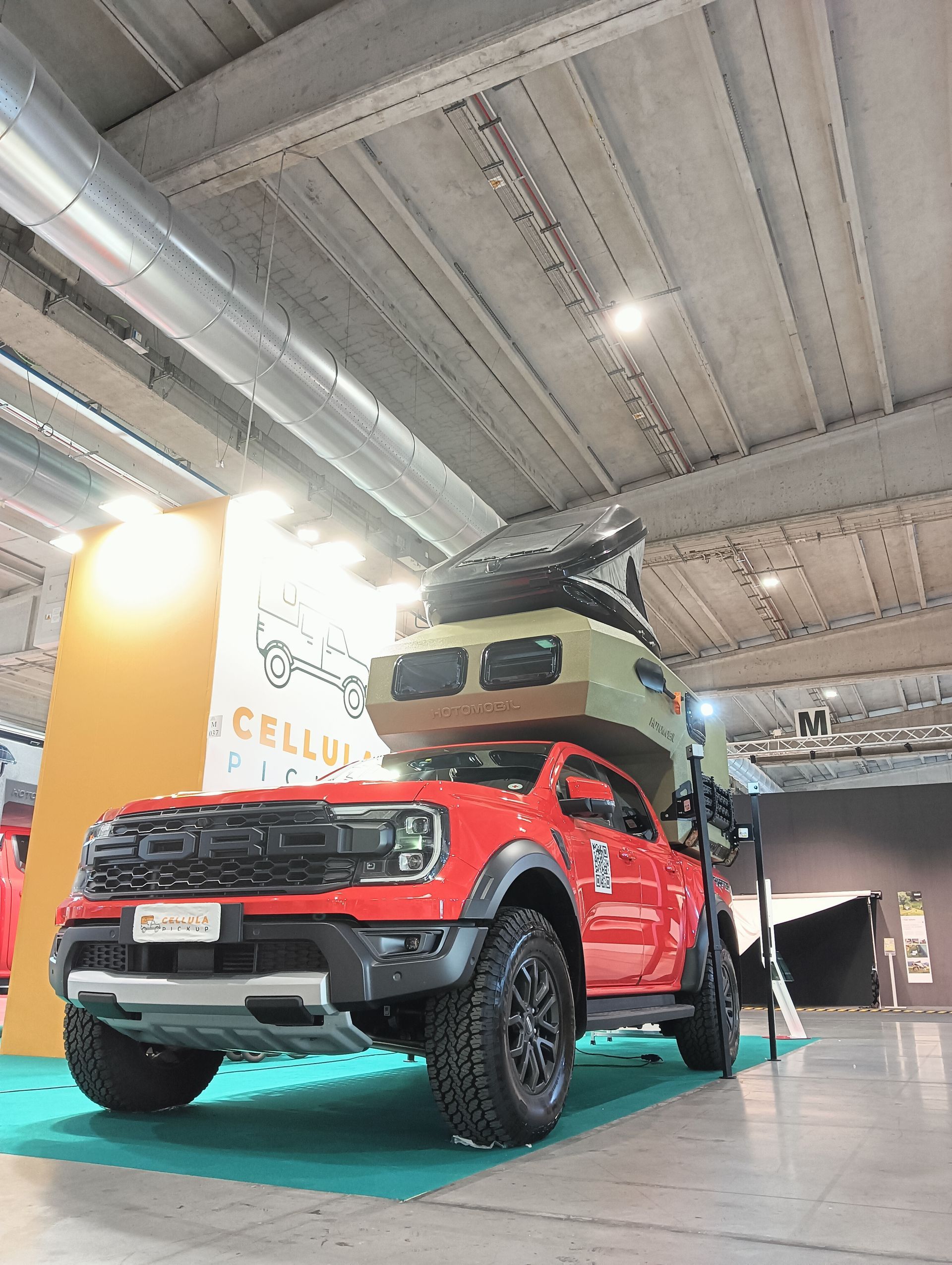 Un camion rosso con una tenda sopra è esposto a un salone dell'auto.