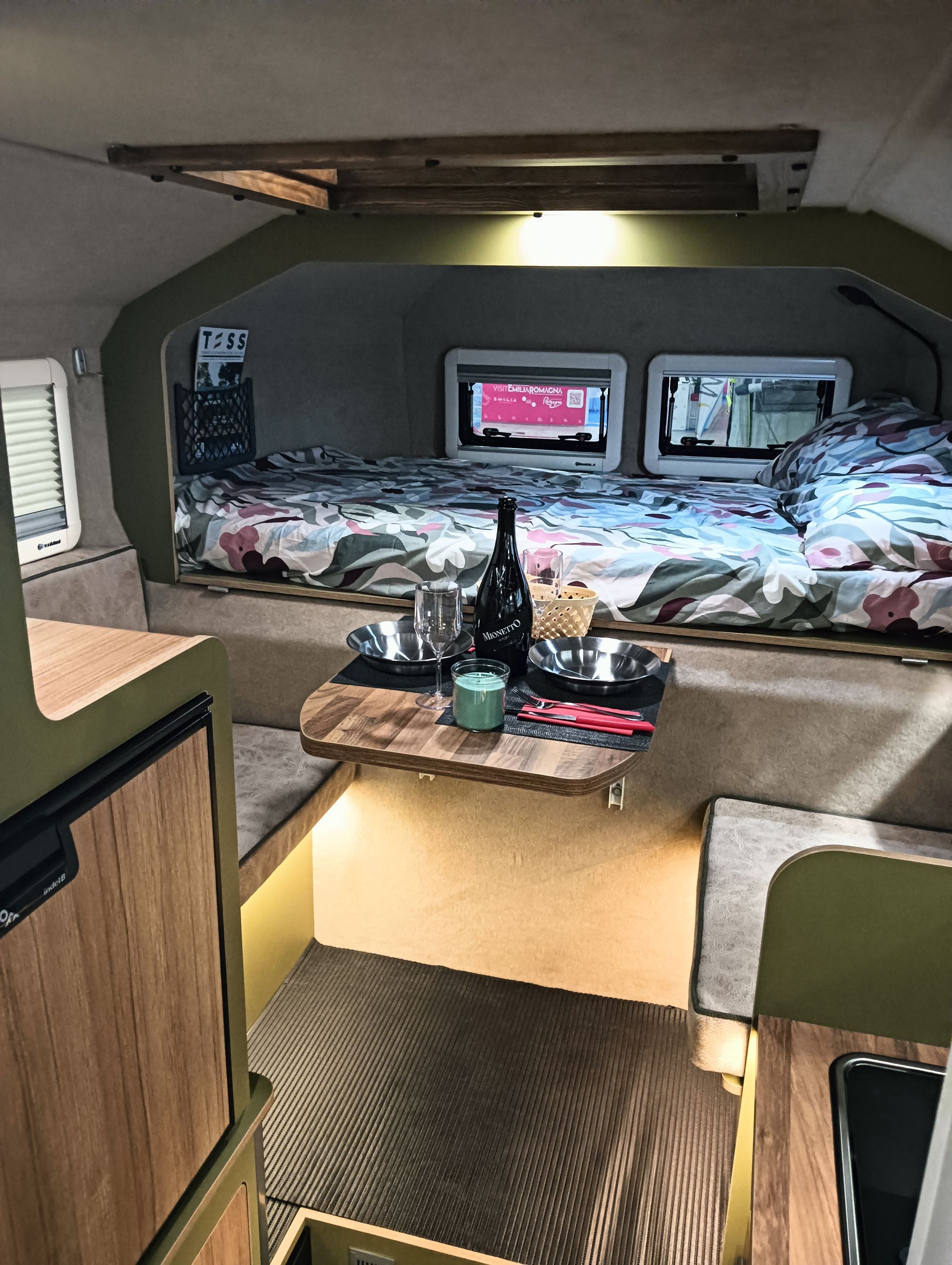 Un camper con un tavolo e una bottiglia di vino sopra.