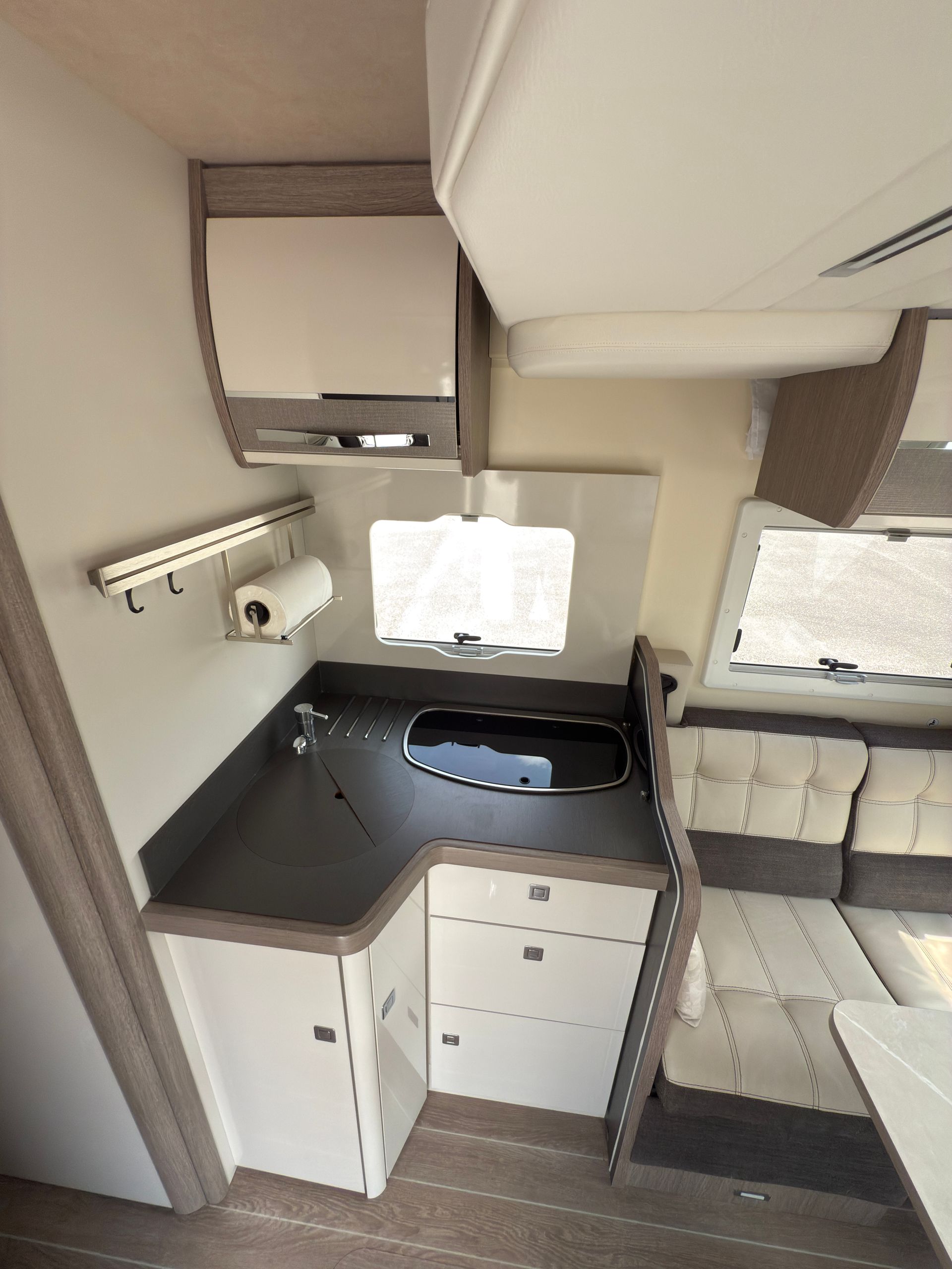 Vista interna della cucina di un camper con mobili, lavello e piano cottura.