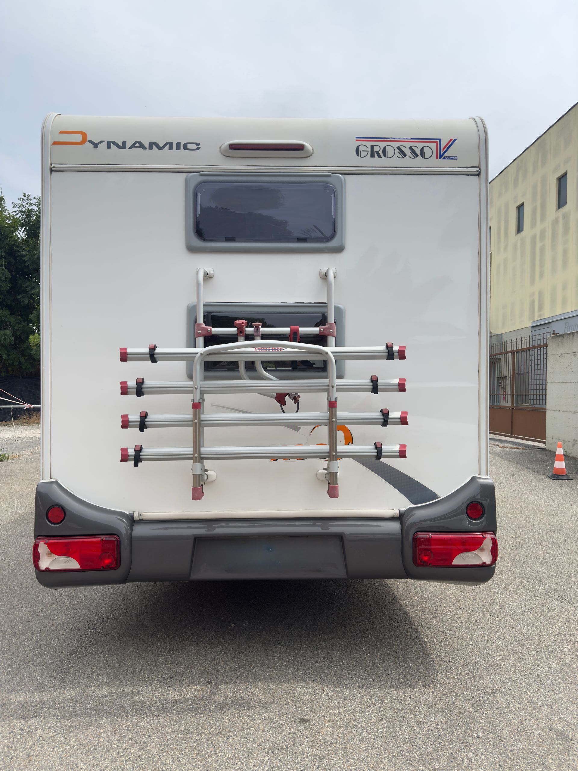 Camper bianco con portabici sul retro, parcheggiato all'aperto.
