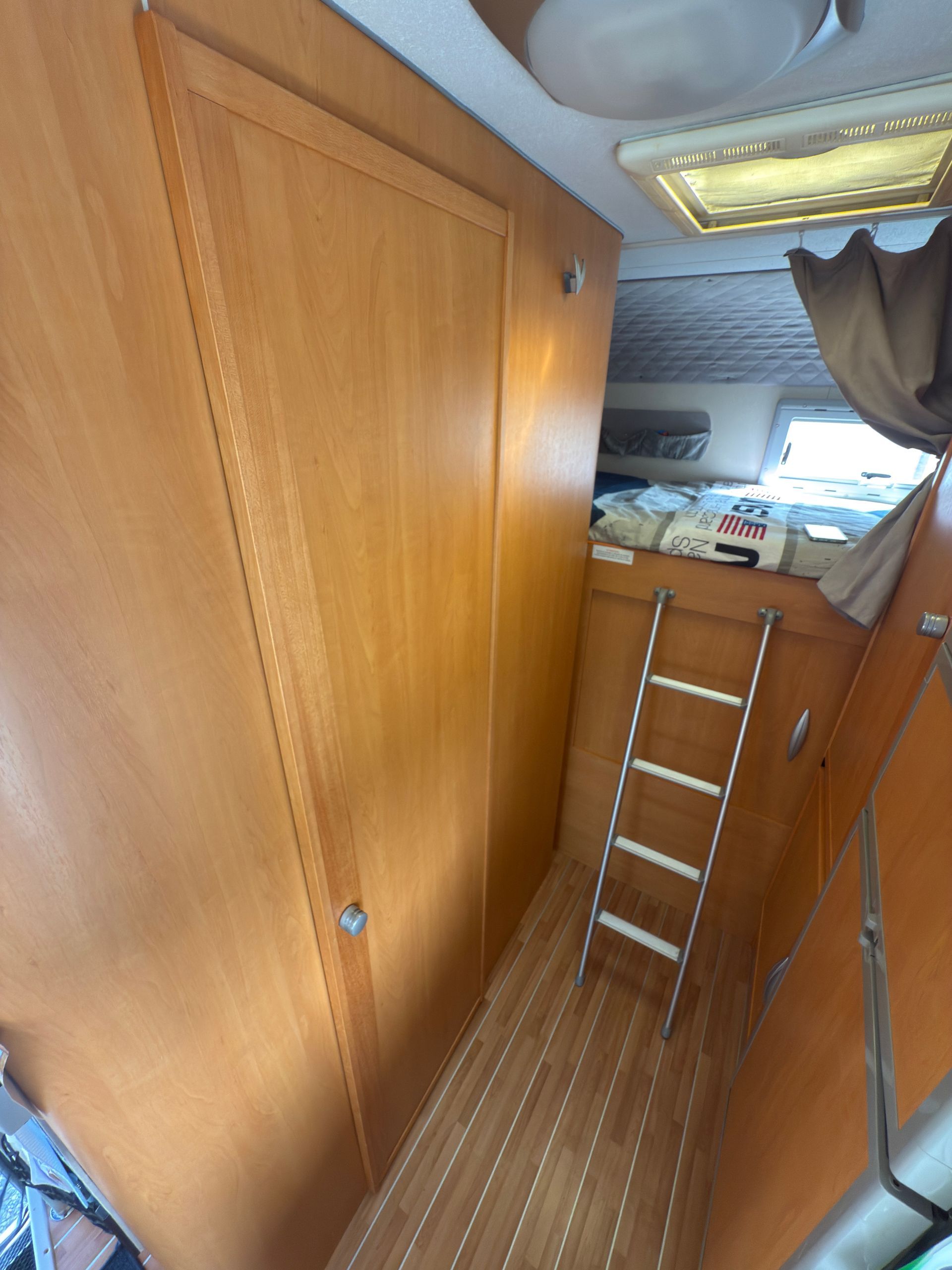 Interno in legno di una barca con porta, scala e pavimento in legno.