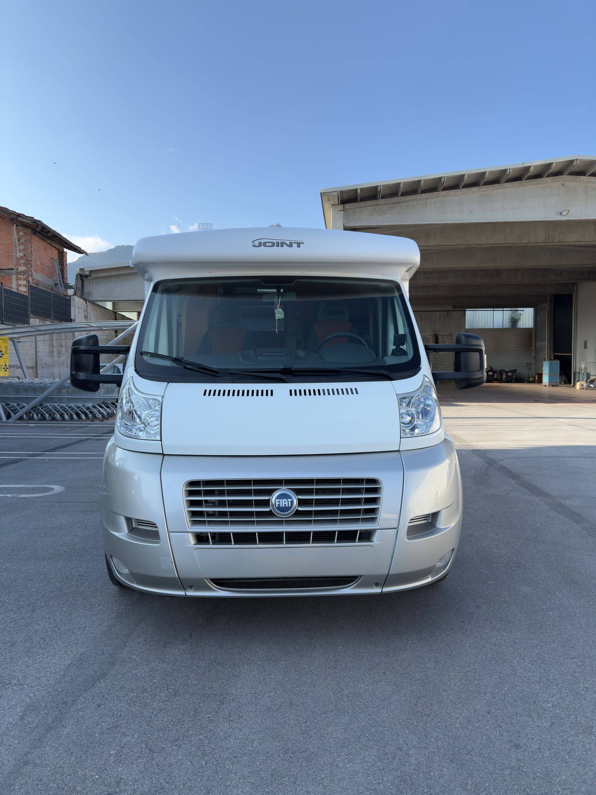 Camper bianco e argento parcheggiato fuori da un edificio.