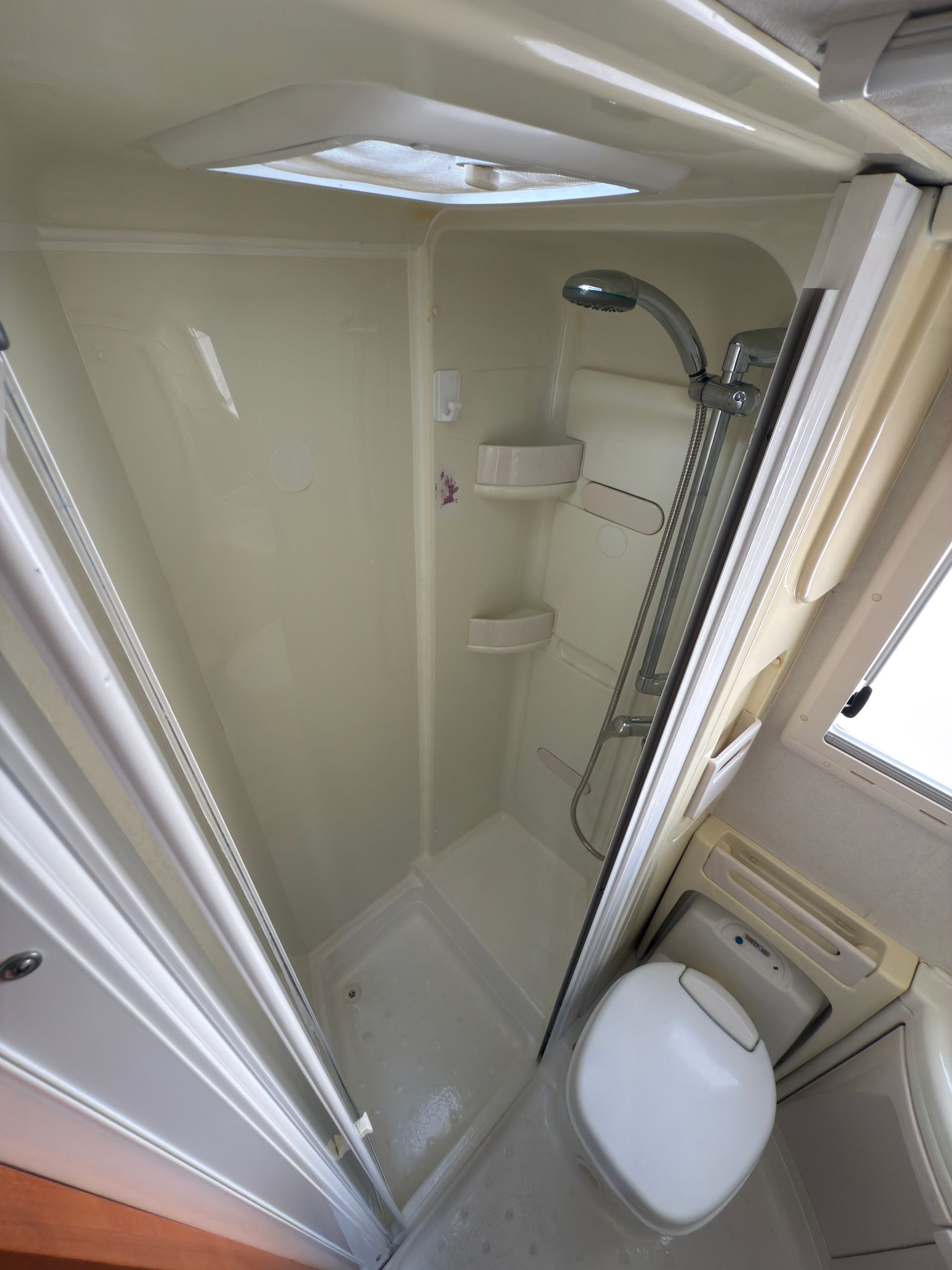 Bagno per camper con doccia, WC e lucernario.