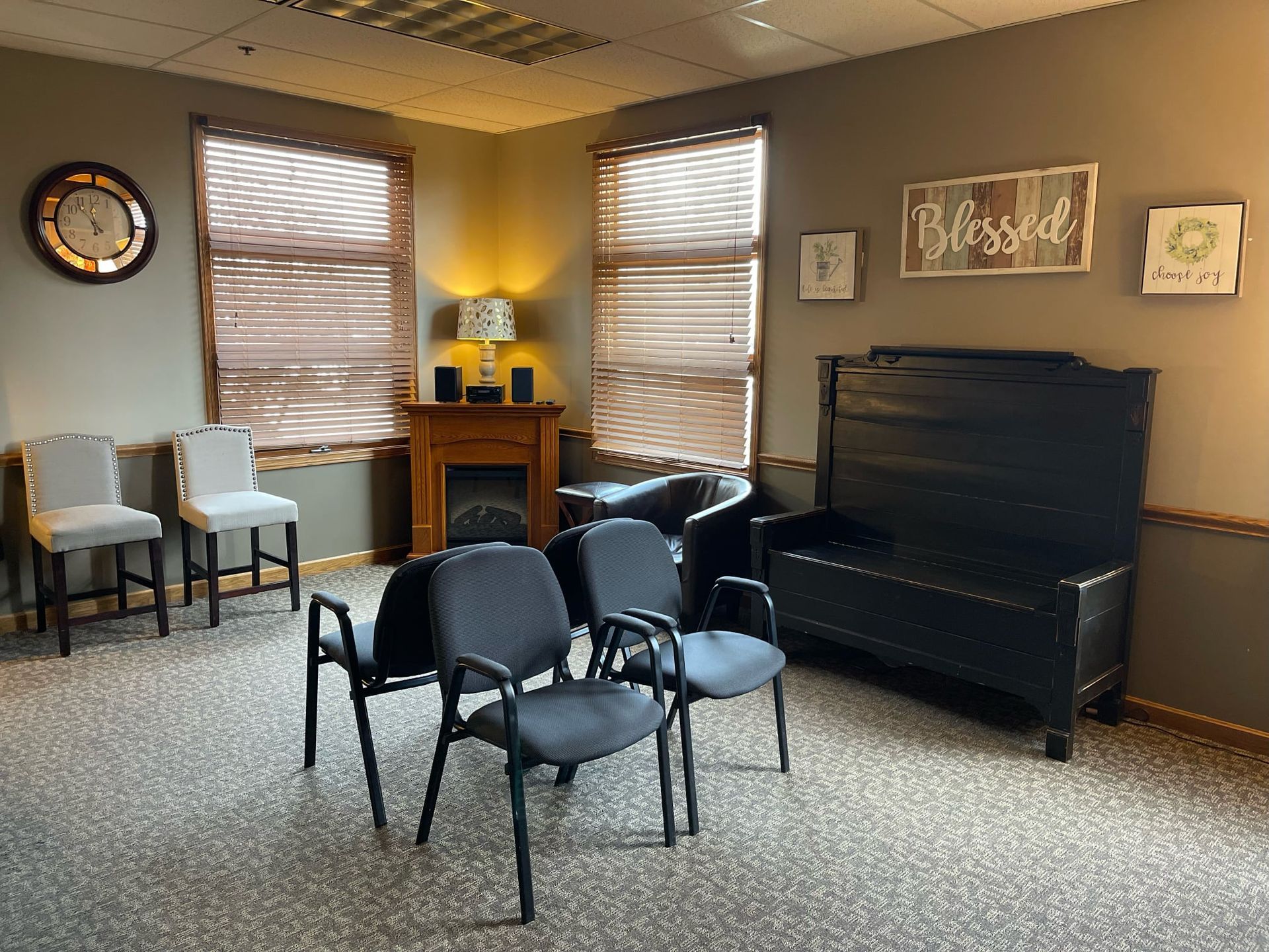 Waiting room with chairs, bench, fireplace, and decor; neutral colors.