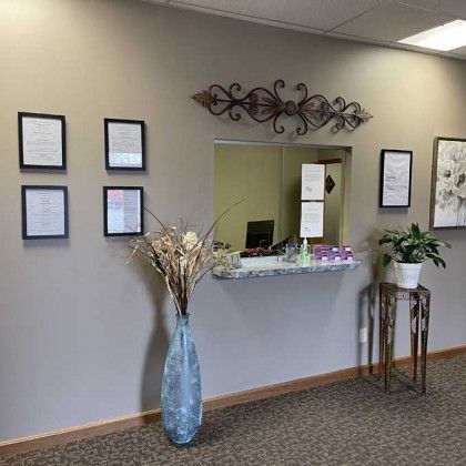 Reception area with a counter, framed documents, decorative elements, and a plant.