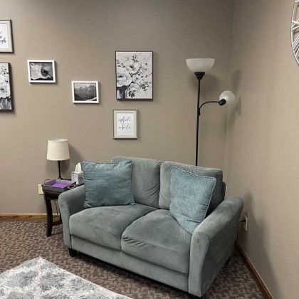 A cozy, light blue loveseat in a neutral-toned room with framed art, a lamp, and a standing lamp.