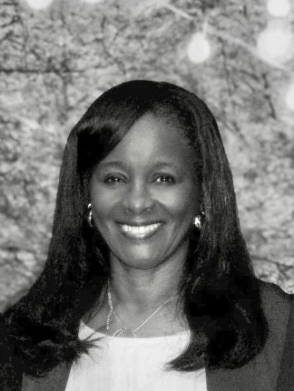 Smiling Black woman with long hair, wearing a necklace, and earrings.