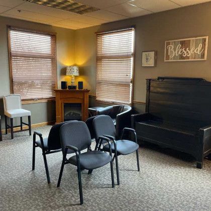 A room with chairs, windows, and a fireplace. Earth-toned walls and a 