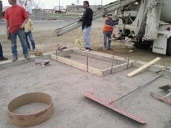 Workers pouring concrete with building materials and tools on-site for a construction.
