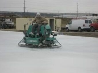 Worker using power trowel to smooth concrete slab with quality building materials on jobsite.