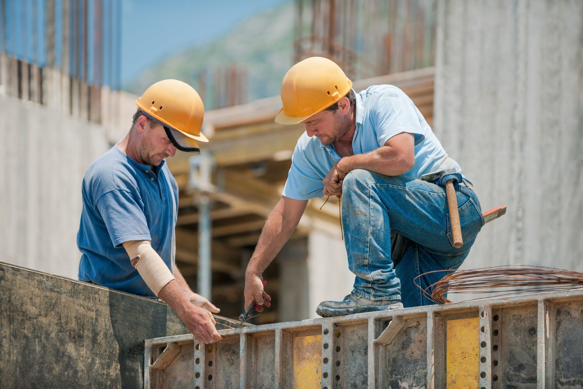 Two construction workers are working on a wall at a construction site.