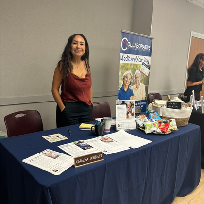 Woman at table with Cranberry sign, smiles, displays information at a business event.