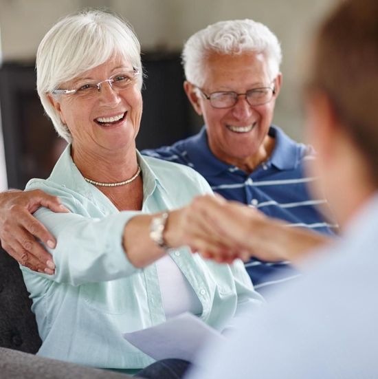 senior couple with woman shaking hands with an advisor whose face you can't see