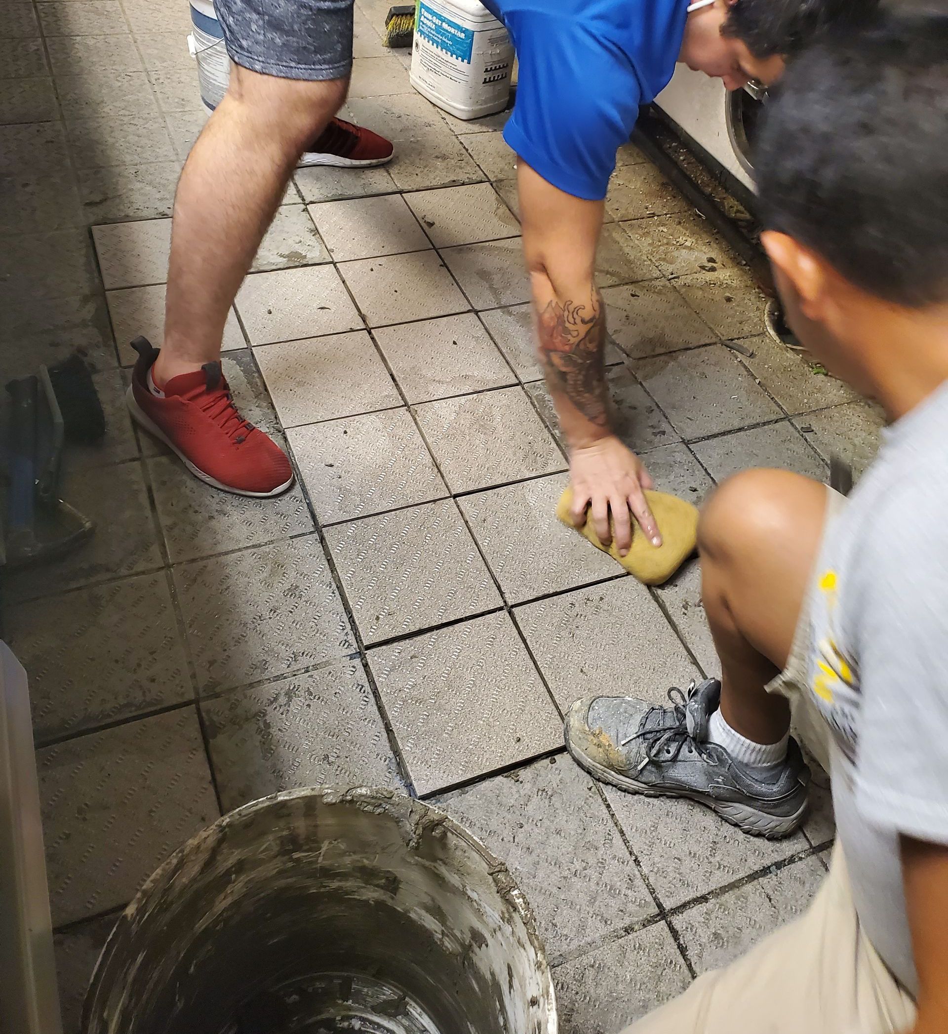 a man in a blue shirt is cleaning a tile floor with a sponge
