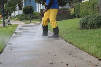 a yellow high pressure washer is spraying water on a brick sidewalk