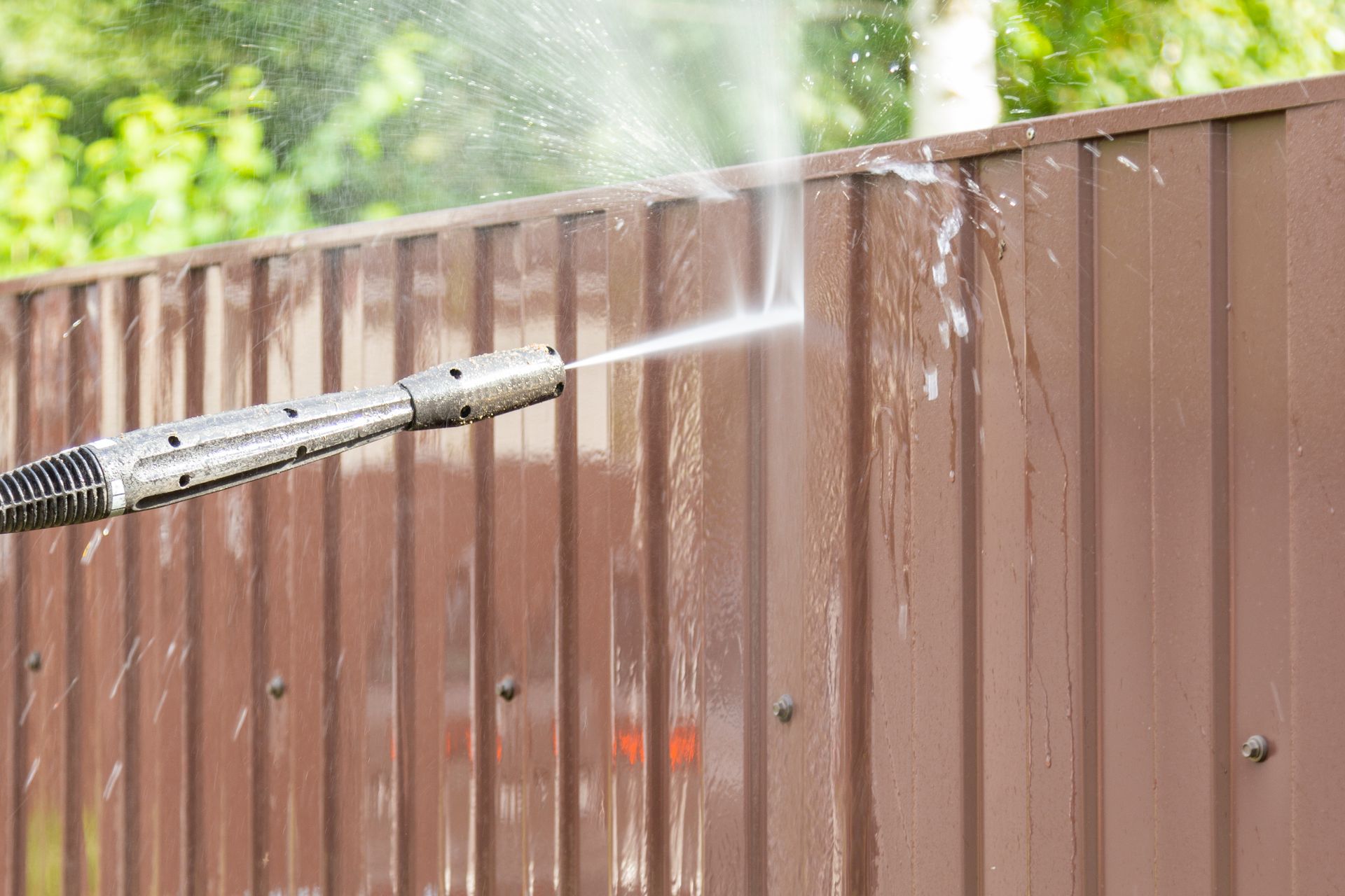a fence is being cleaned with a high pressure washer