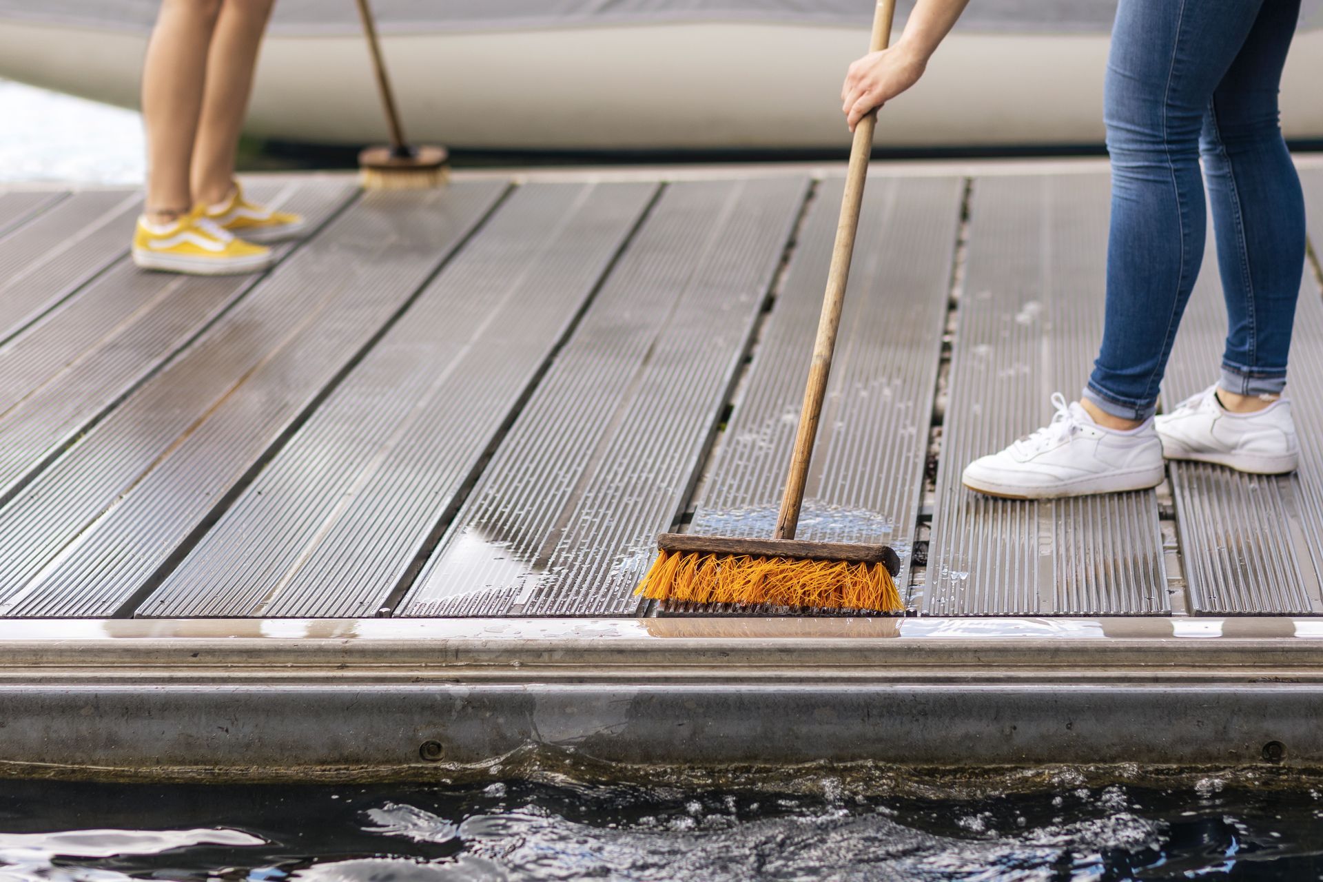 people clean a wooden boat dock