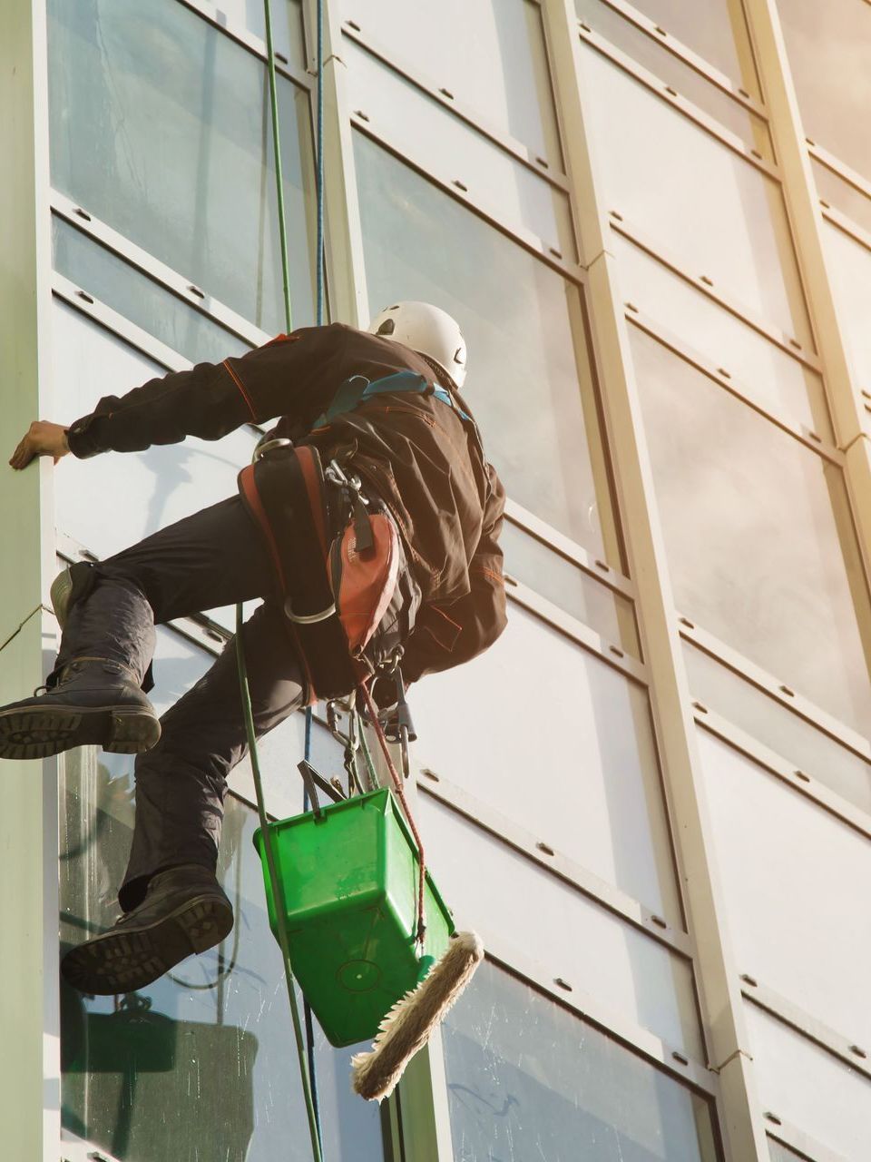 a man is cleaning a building with a green bucket