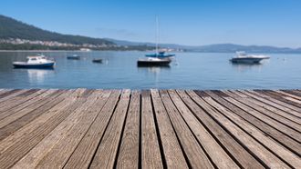 a wooden dock with boats in the water in the background