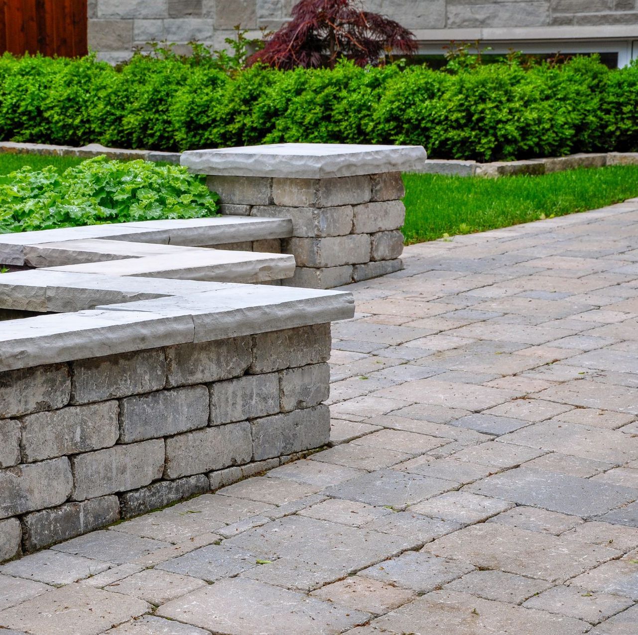 a brick walkway with a stone wall and benches