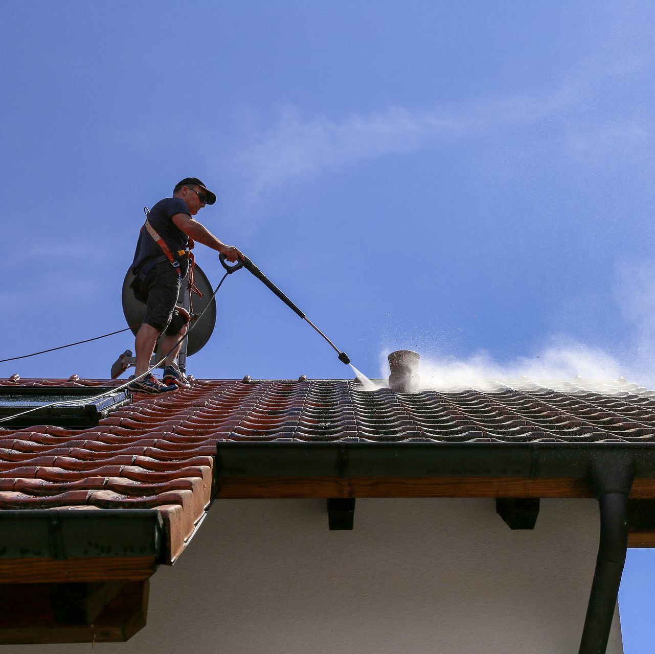 a man is cleaning a roof with a high pressure washer